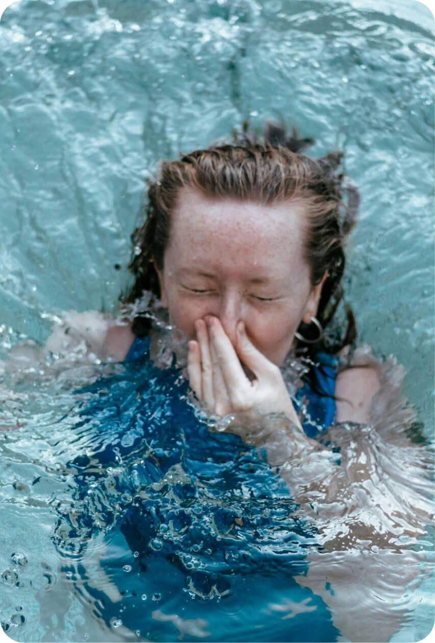 Person holding their nose before diving into cold pool water